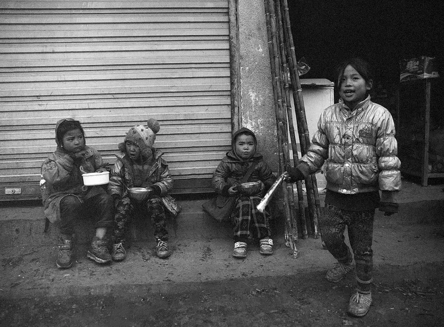 Children outside a shuttered shopfront, Liangshan Prefecture.