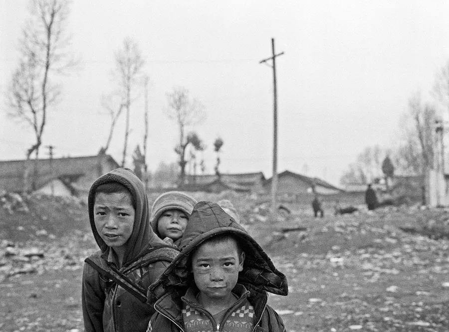 Three children on a village road, Liangshan Prefecture.