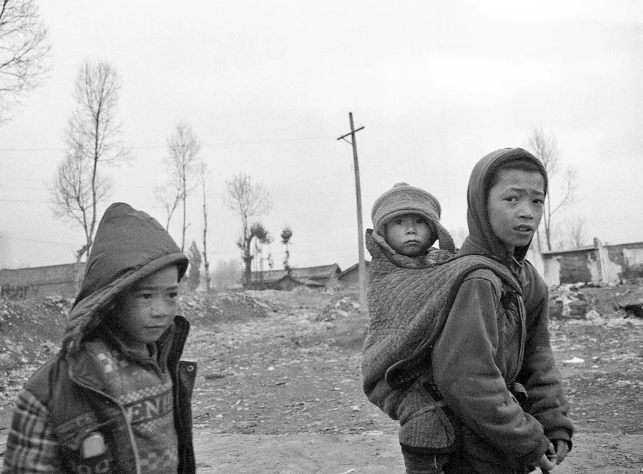 Two children on a dirt road in winter, Liangshan Prefecture.