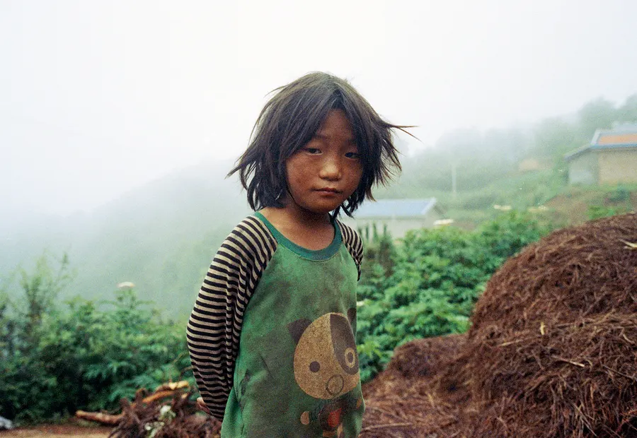 A girl on a hillside in the mist, Liangshan Prefecture.