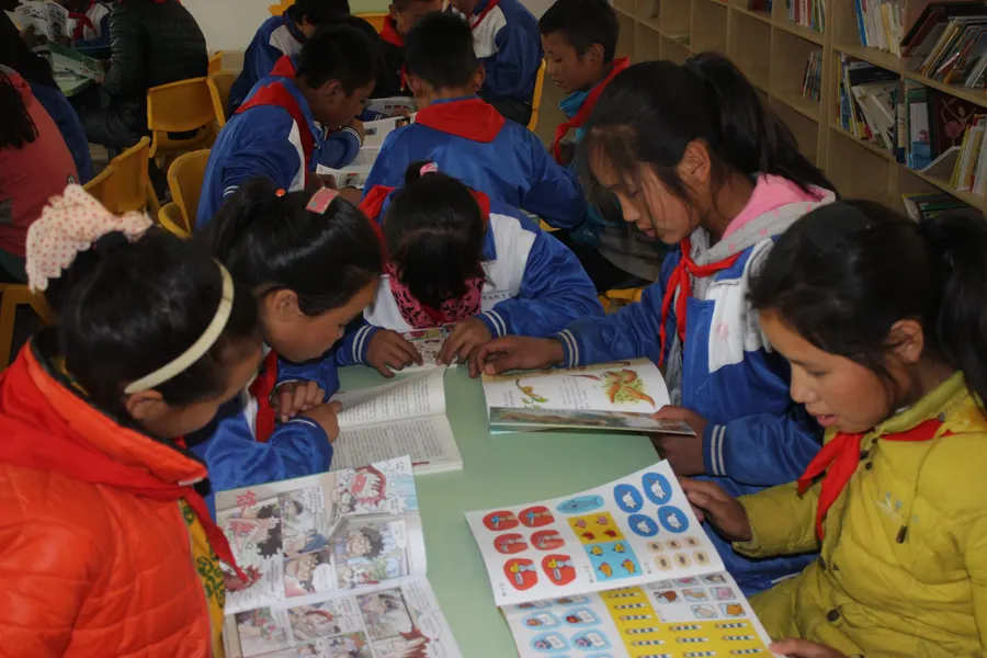 Children reading together at the library table.